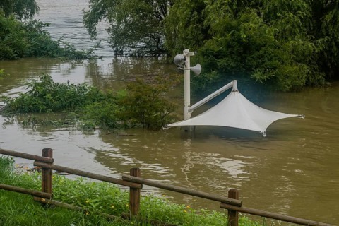 White awning over flooded river where picnic table has been submerged under water from monsoon
