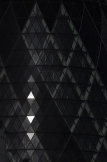 The Gherkin skyscraper building close up of window details with sunlight illuminating three