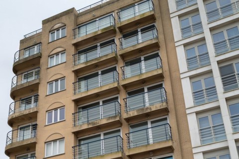 Multi-storey residential building with balconies and architectural decorations under a cloudy sky,