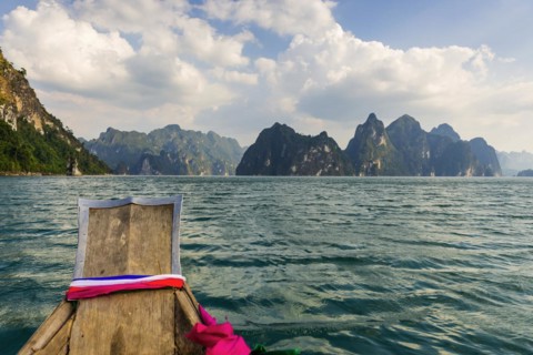 Traditional longtail boat in front of limestone rocks in Cheow Lan Lake in Khao Sok National Park,
