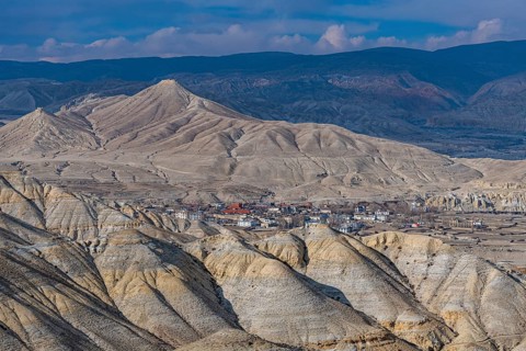 Lo Manthang, capital of Upper Mustang, viewed from a distance amidst a barren desertic landscape,