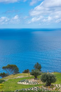 Peaceful sea view with terraced garden, green grass areas, rocky beds and trees in spring, rock