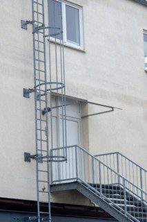 Metal staircase and safety ladder on the facade of an industrial building