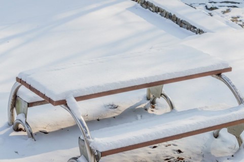 A wooden bench with metal framework covered in a thick layer of snow, in South Korea