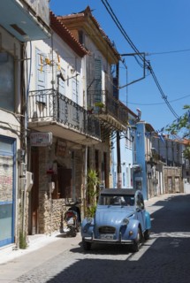 A quiet alleyway scene with old buildings, a vintage car and a motorbike, Citroen 2 CV, duck,