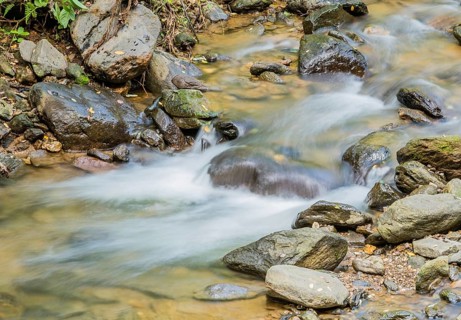 Small water fall cascading down rocks in the middle of a small mountain stream in Guam