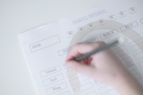 Diabetes log, daily log of food and insulin administration, food log, hand of a child holding a pen