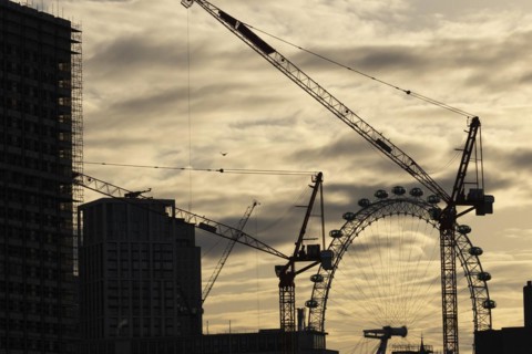 London Eye or Millennium Wheel tourist observation wheel at sunsetwith industrial cranes and