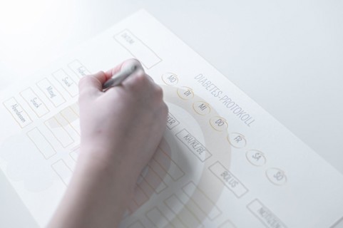 Diabetes log, daily log of food and insulin administration, food log, hand of a child holding a pen