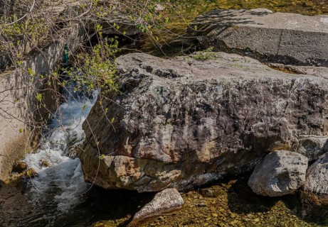Water cascades down beside a large shaded rock, in South Korea
