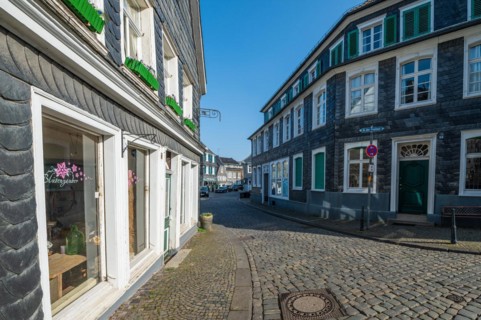 A clearly cobbled street with old half-timbered houses and a blue sky above, Graefrath, Solingen,