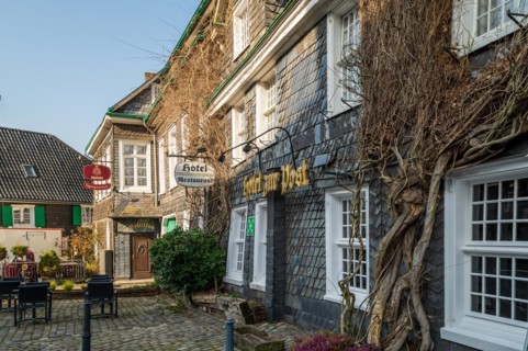Old half-timbered house with the sign of 'Hotel Wirtshaus zum Scharfenstein' next to a street lamp,