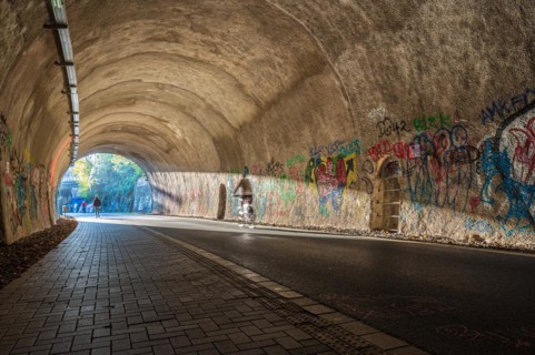 A cyclist rides through a graffiti tunnel with focussed lighting, Nordbahntrasse, Elberfeld,