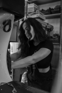 Determined woman mechanic working on the engine of a moped italian vintage scooter in a garage,