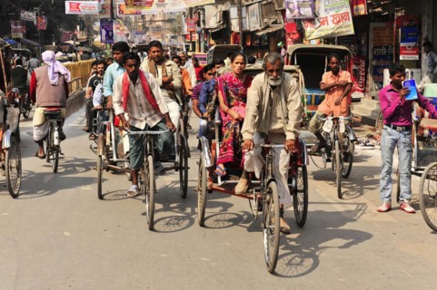 Busy street scene with many cycle rickshaws and passers-by, Varanasi, Uttar Pradesh, India, Asia