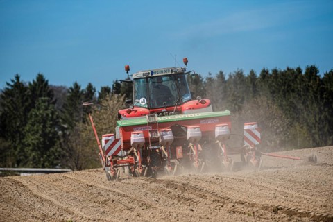 A tractor ploughs a field under a clear sky with swirling dust, Wuelfrath, Mettmann, North