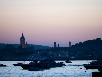 Boats anchoring in a bay, church towers, evening mood after sunset over Rab, town of Rab, island of