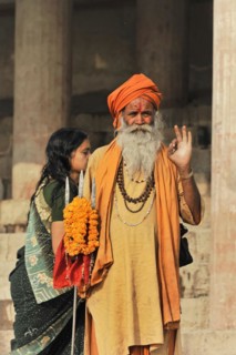 Man in orange-coloured traditional dress blessing woman with flower wreath, Varanasi, Uttar