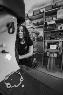 Serious woman mechanic disassembling a part on a moped italian vintage scooter motorcycle in the