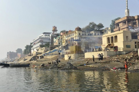 Urban riverbank with people living everyday life, framed by a culturally rich urban landscape,