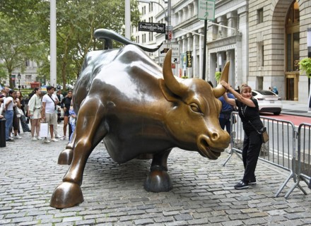 Tourist pulling on the horn of the Wall Street bull, Financial District, Lower Manhattan, New York