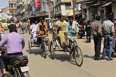 People travelling in cycle rickshaws on a busy street with shops, Varanasi, Uttar Pradesh, India,