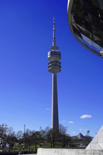 The Olympic Tower in Munich is reflected in the facade of a modern building, BMW WELT, Munich,