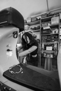 Woman mechanic focusing on repairing the inside of a moped italian vintage scooter in a workshop,