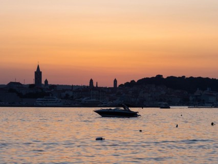 Boats anchoring in a bay, church towers, evening mood after sunset over Rab, town of Rab, island of