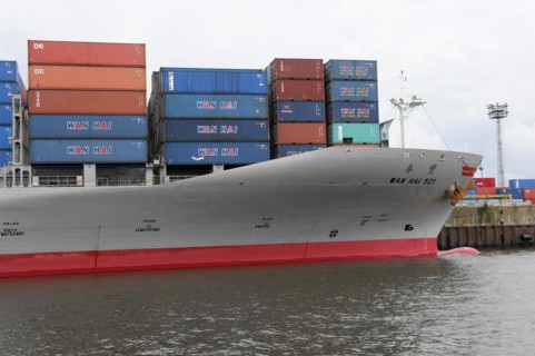 Bow of a large container ship WAN HAI 501 with red stripe and stacked containers, Hamburg,