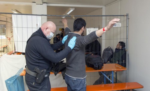 Refugees are searched by federal police officers after their arrival at Rosenheim station,