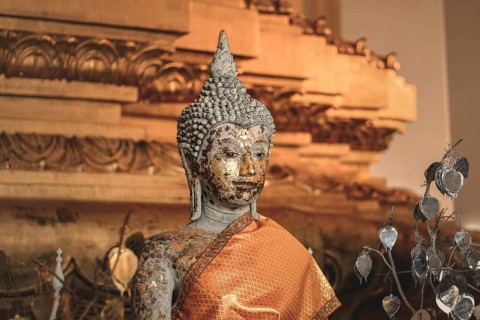 Gilded Buddha statue with worn texture wrapped in orange fabric. Ayutthaya, Thailand, Asia