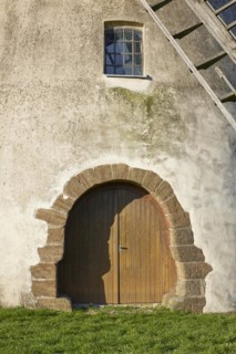 Entrance gate, window and part of the wings of the windmill Auf der Hoechte under a cloudless blue