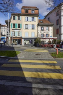 Old pastel-coloured houses with white windows and wooden shutters and the Cafe Vieil Ouchy on a