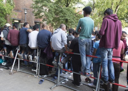 Refugees from Syria wait behind barriers in the central reception centre for asylum seekers at the