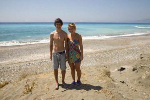 Model released smiling brother and sister twins stand on sandy beach together, Rhodes, Greece,