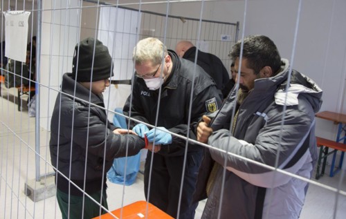 Refugees are searched by federal police officers after their arrival at Rosenheim station,