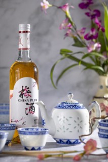 Asian tea set with blue patterns and a bottle of China plum wine