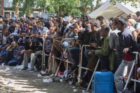 Refugees from Syria wait behind barriers in the central reception centre for asylum seekers at the
