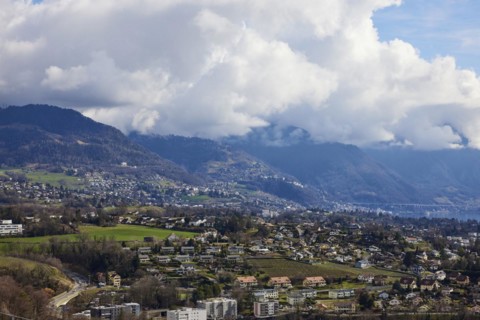 View of the outskirts of Vevey and mighty white spring clouds moving over mountains near Jongny,