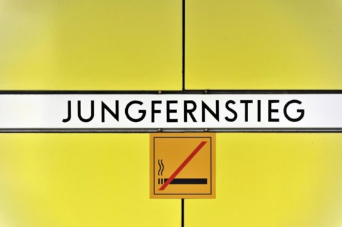 Sign of the underground station 'Jungfernstieg' with no smoking sign on yellow background, Hamburg,