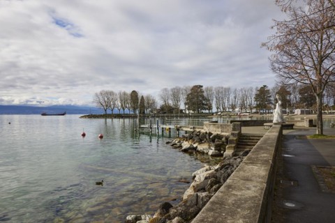View of Lake Geneva with cargo ship from the lakeside promenade with the statue of the Virgin of
