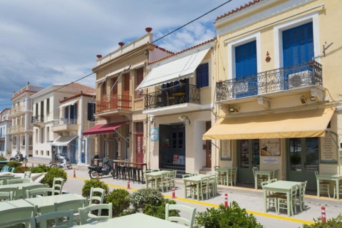 Mediterranean street with colourful buildings, an outdoor restaurant and a clear blue sky,