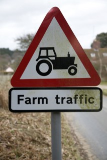 Red triangular road sign for farm traffic, UK