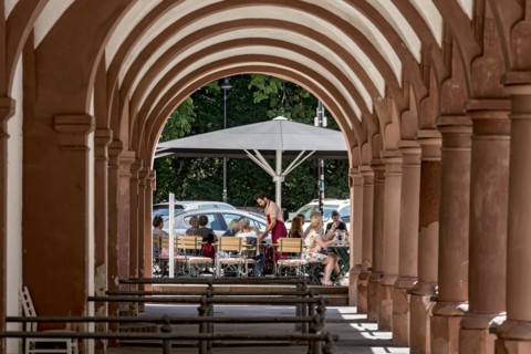 Restaurant and street cafe with waiter and guests, historic market arbours, archway with columns,
