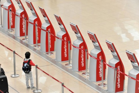 A child standing in front of self-service check-in machines in an airport queue, Hamburg, Hanseatic