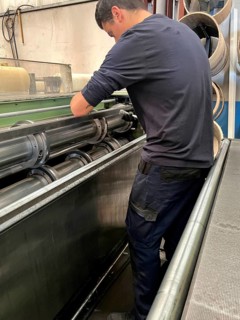 Vertical portrait of a man placing the blades for cutting sheet metal on a metal cutting machine.