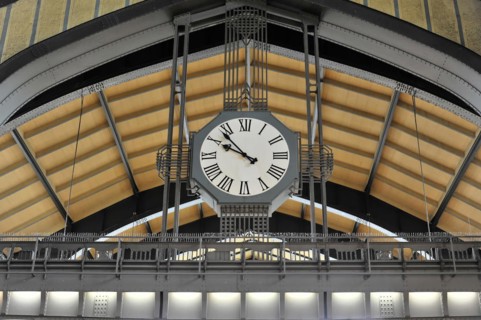Modern railway station clock on a vaulted ceiling with glass and metal structures, Hamburg,