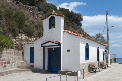 Small white chapel with blue accents located next to a quiet street, Holy Cross Church, Poros,