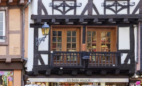 Balcony and window on a half-timbered house and the shop La Belle Alsace in the old town centre of